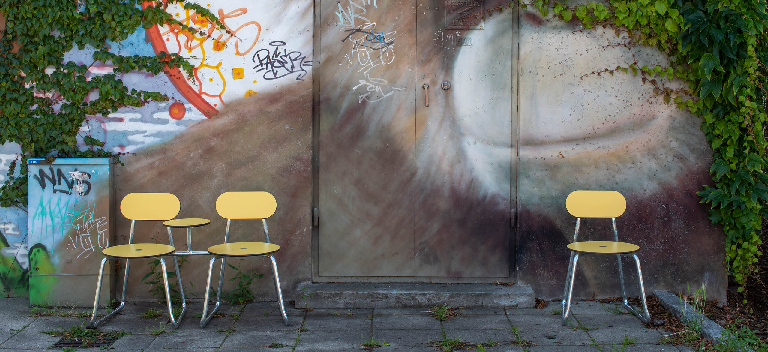 Tre gule Plateau City Chairs op ad en væg med graffiti