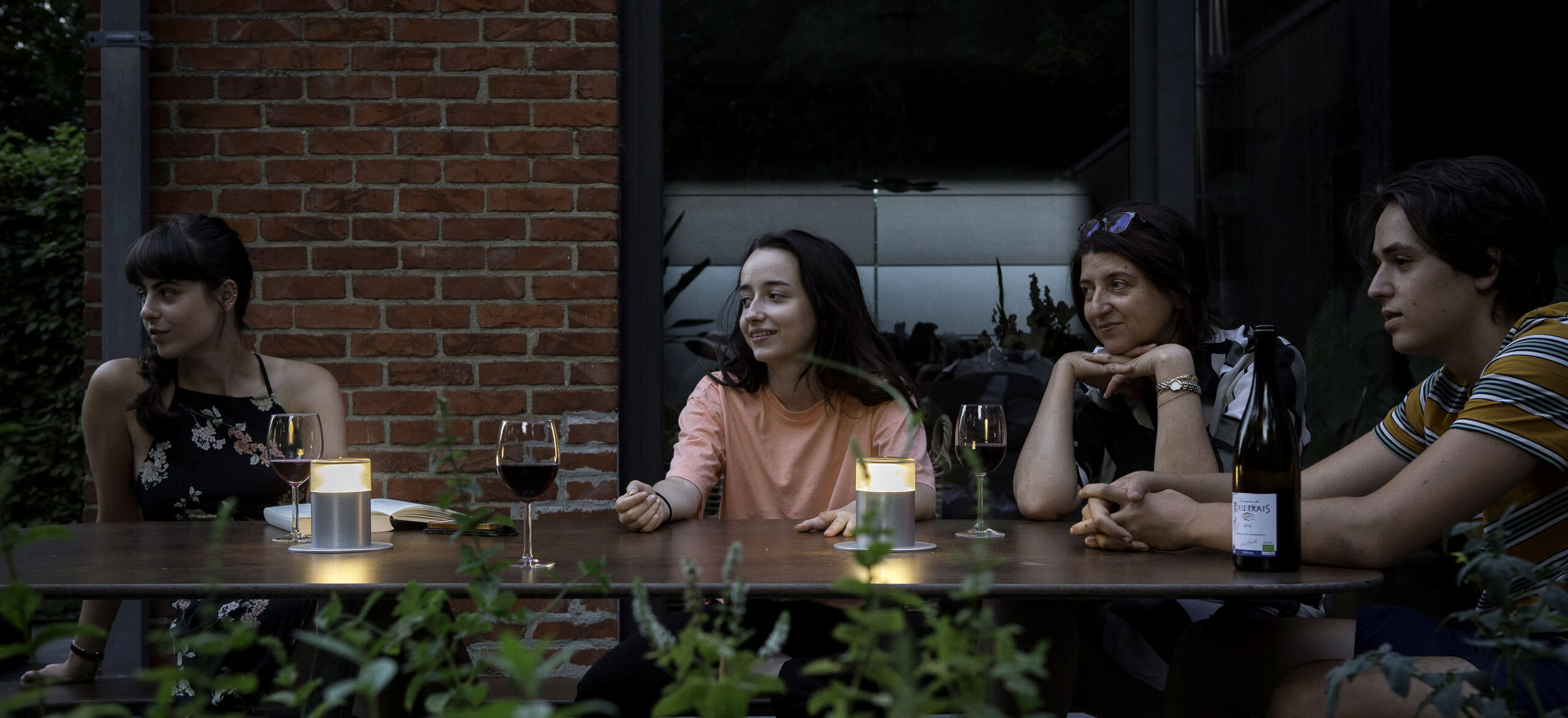Fire kvinder rundt om et bord, de drikker vin og snakker. Belysningen er to Plateau Point Sun